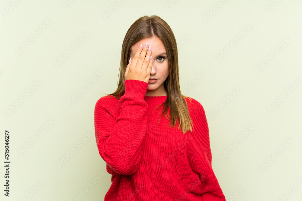 Teenager girl over isolated green background covering a eye by hand Teenager girl over isolated green background covering a eye by hand