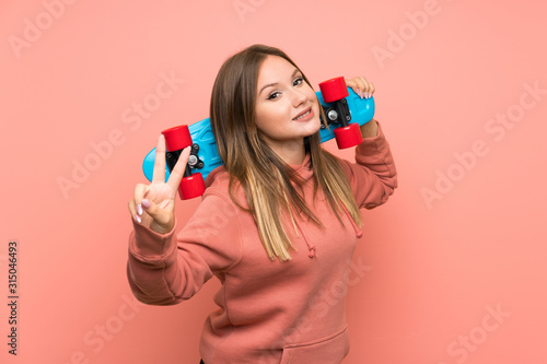 Teenager girl with skate over isolated pink background