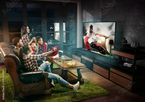 Group of friends watching TV, football match, leisure activity. Emotional men and women cheering for favourite team, look on fighting for ball. Concept of friendship, sport, competition, emotions.