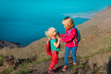 happy little girls high five while travel in mountains near sea, family hiking