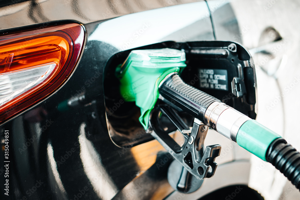 Man pumping petrol at gas station into vehicle. Hand holding a pistol pump. Man pumping petrol at gas station into vehicle. Hand holding a pistol pump.