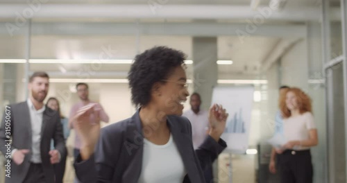 Backside view of happy female boss entering office room with good news. Office staff congratulating woman team leader with successful bargain and giving her five. Success amd positive emotions.
