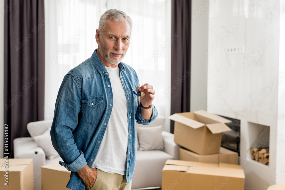 mature man holding keys and looking at camera in new house mature man holding keys and looking at camera in new house