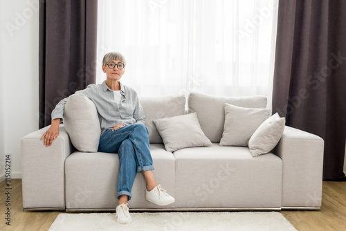 mature woman in glasses sitting on sofa in new house © LIGHTFIELD STUDIOS