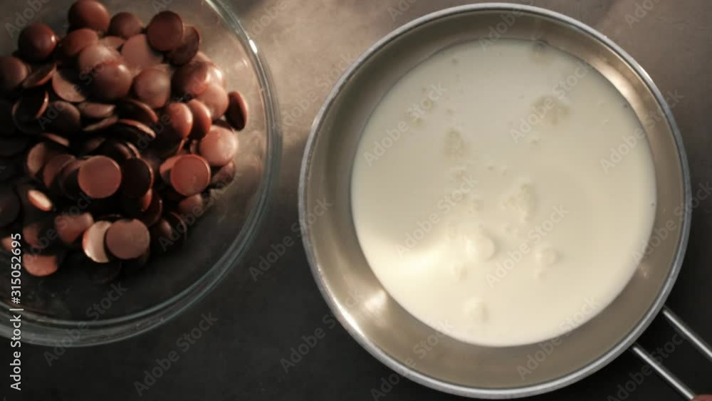 Topview of dark milky chocolate and cream, hand placing a pan Topview of dark milky chocolate and cream, hand placing a pan