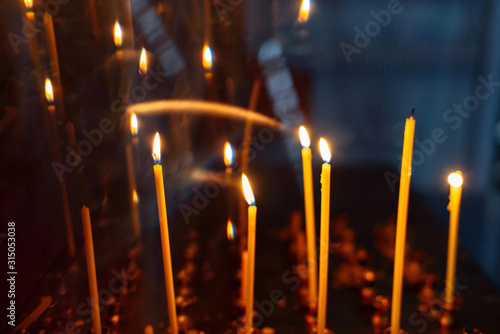 burning yellow candles in the Orthodox Church