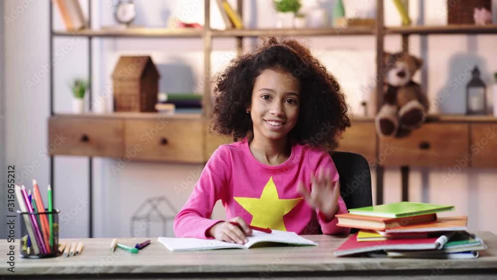smiling african american child doing homework and waving hand smiling african american child doing homework and waving hand