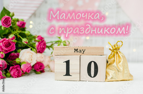 May 10 date on a wooden calendar, roses, holiday flags and a garland on a white background. Mother's day concept