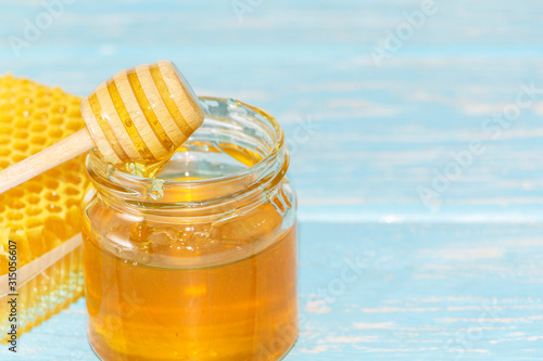 Honey on the background of honeycomb. Honey in a glass jar and honeycomb photo