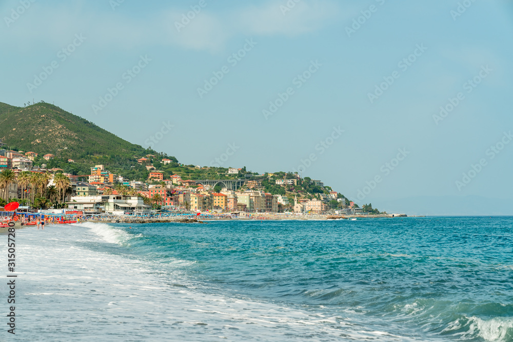 view from the sea of Varazze beach, a village of northern Italy, on the sea, during a beautiful summer day, landscape beach with typical sun parasol and wonderful mediterranean wave.Copy space.