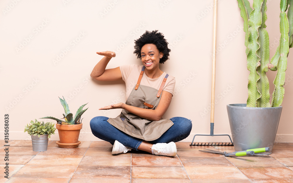 Gardener woman sitting on the floor holding copyspace to insert an ad Gardener woman sitting on the floor holding copyspace to insert an ad