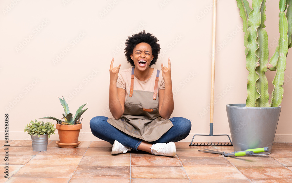 Gardener woman sitting on the floor making rock gesture Gardener woman sitting on the floor making rock gesture