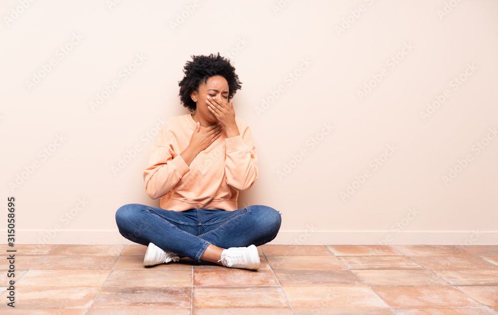 African american woman sitting on the floor is suffering with cough and feeling bad