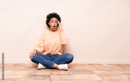 African american woman sitting on the floor has just realized something and has intending the solution