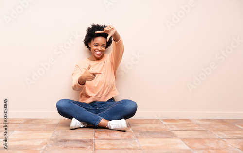 African american woman sitting on the floor focusing face. Framing symbol
