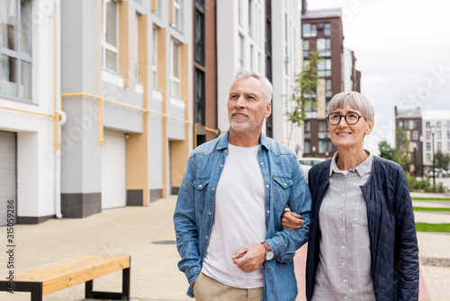 Obraz na plátně mature man and smiling woman walking near new houses