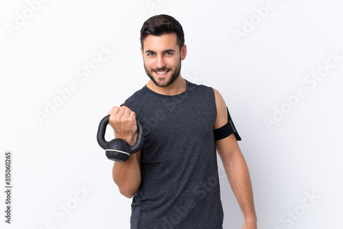 Young sport handsome man with beard over isolated white background making weightlifting with kettlebell © luismolinero
