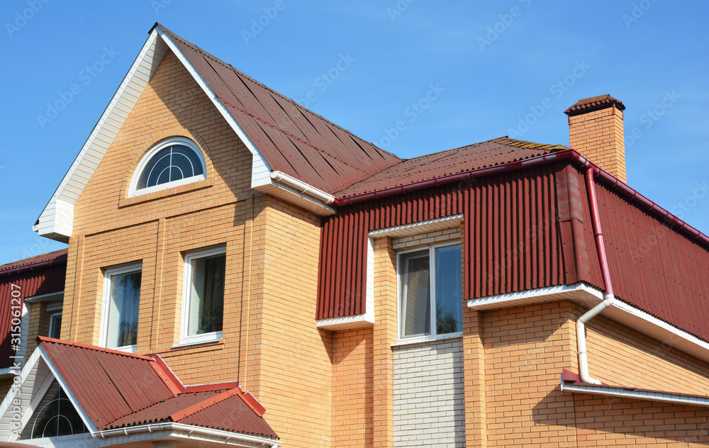Brick house rooftop with attic windows and rain gutter pipeline
