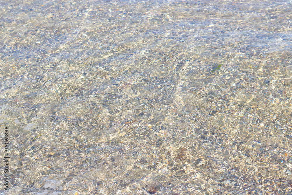 clear sea water through which the sandy bottom is visible clear sea water through which the sandy bottom is visible