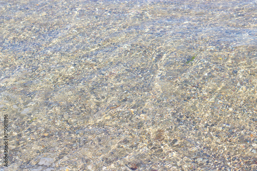 clear sea water through which the sandy bottom is visible