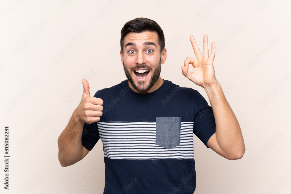Young handsome man with beard over isolated background showing ok sign and thumb up gesture Young handsome man with beard over isolated background showing ok sign and thumb up gesture
