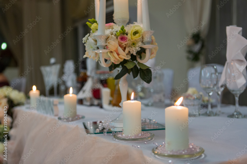 wedding decoration on the wedding table. newlyweds decorated table in a restaurant. beautiful wedding setting with candles, flowers and wedding accessories.