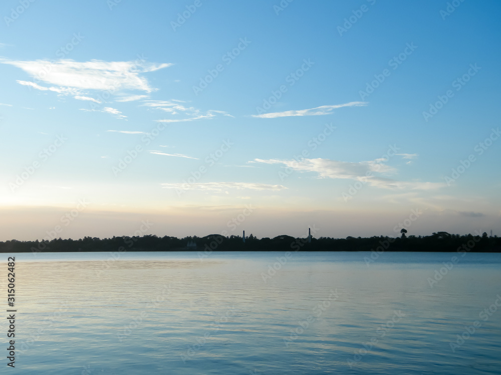 Sunset Skylight Reflection on Lake Water by sun reflector. The moody blues red and yellow in Landscape horizon Background. Dusk to Night Time Lapse Atmospheric mood. Tranquil scene, idyllic atmosphere