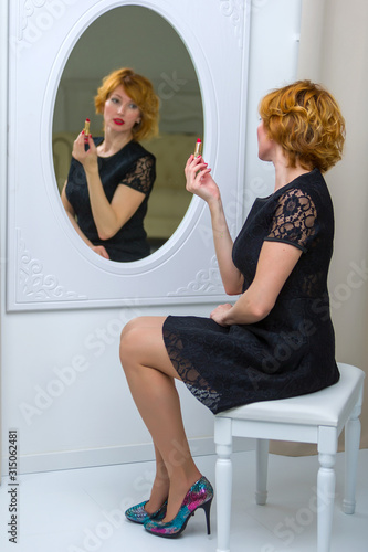 Young woman uses mascara near the mirror. Beauty and care. Studi