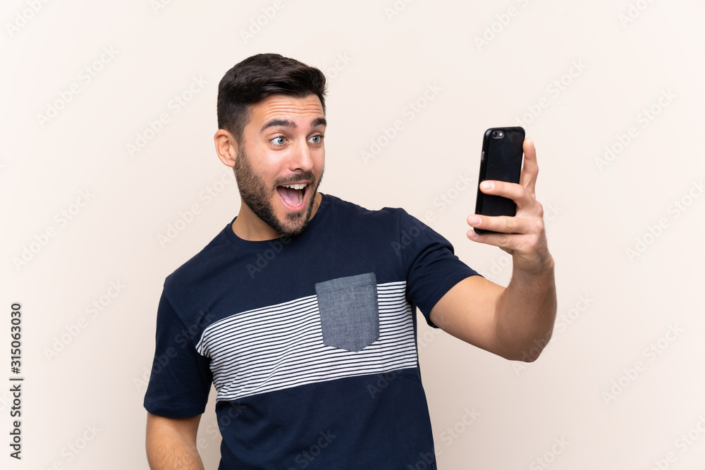 Young handsome man with beard over isolated background making a selfie Young handsome man with beard over isolated background making a selfie