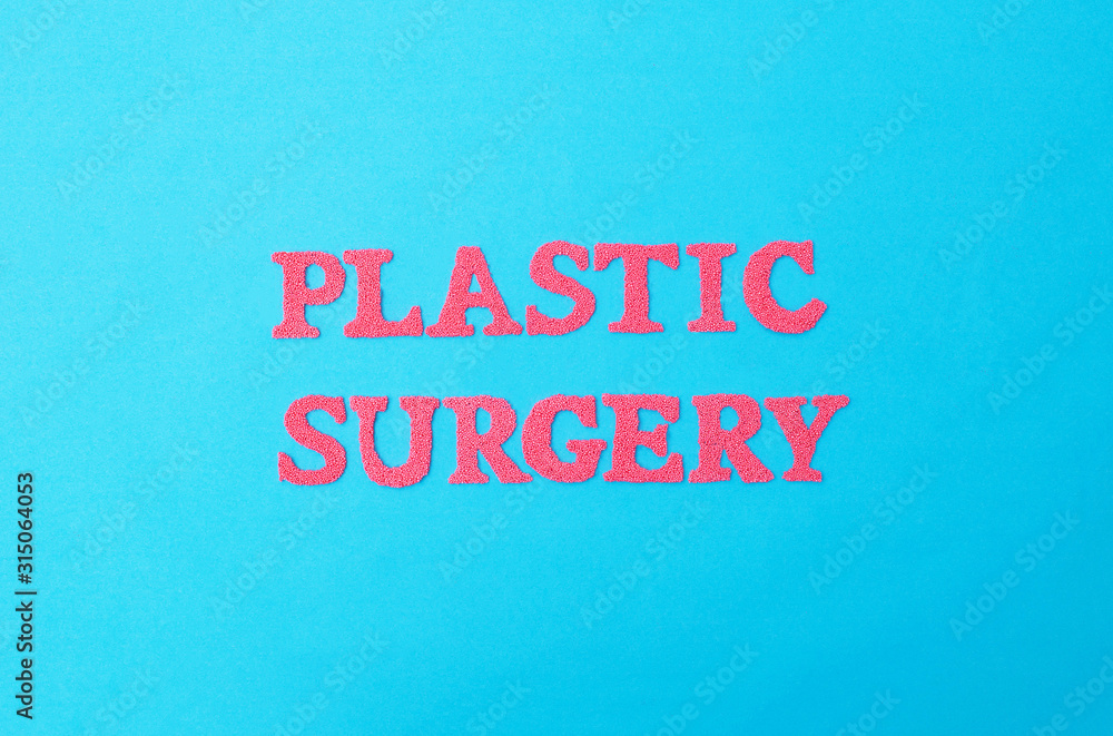 Inscription plastic surgery in red letters on a blue background. The concept of procedures in plastic surgeons abdominoplasty and gynecomastia removal, medicine