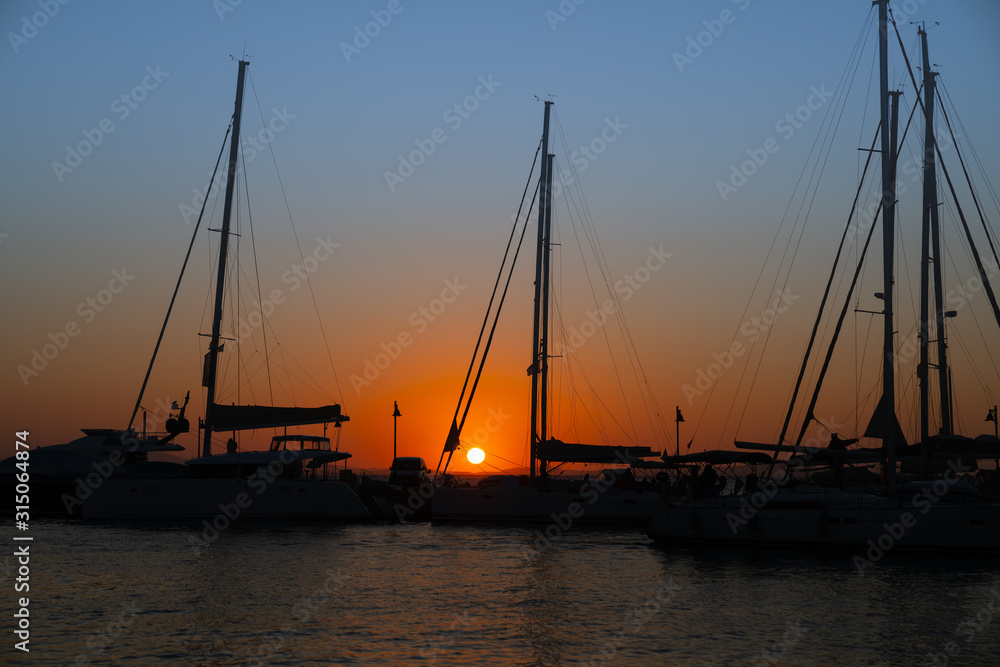 Glow of setting sun through rigging of yachts moored