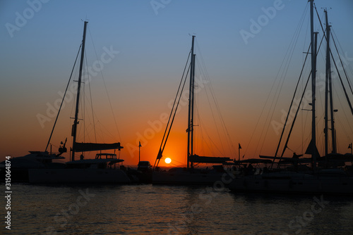 Glow of setting sun through rigging of yachts moored