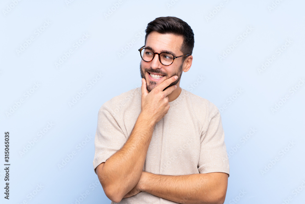 Young handsome man with beard over isolated blue background thinking an idea Young handsome man with beard over isolated blue background thinking an idea