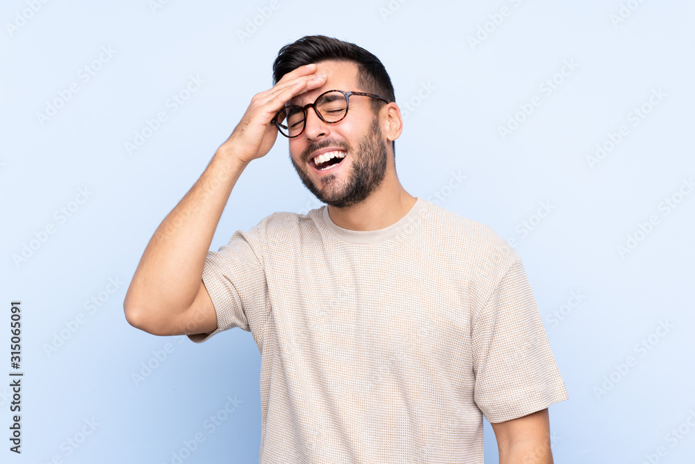 Young handsome man with beard over isolated blue background laughing Young handsome man with beard over isolated blue background laughing