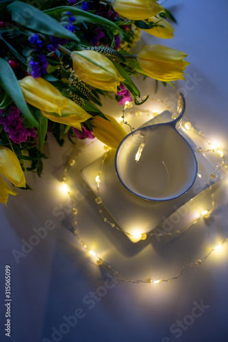 Tea Cup and saucer on a white table with flowers in a bouquet