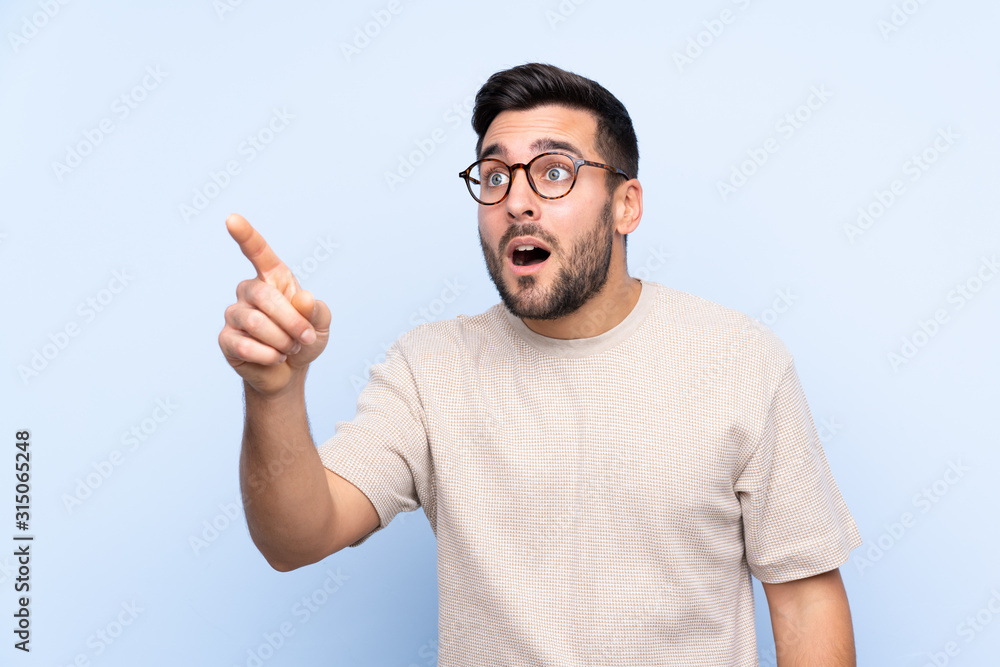 Young handsome man with beard over isolated blue background pointing away Young handsome man with beard over isolated blue background pointing away