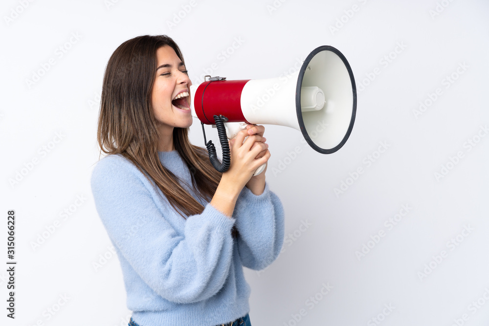 Teenager girl over isolated white background shouting through a megaphone Teenager girl over isolated white background shouting through a megaphone
