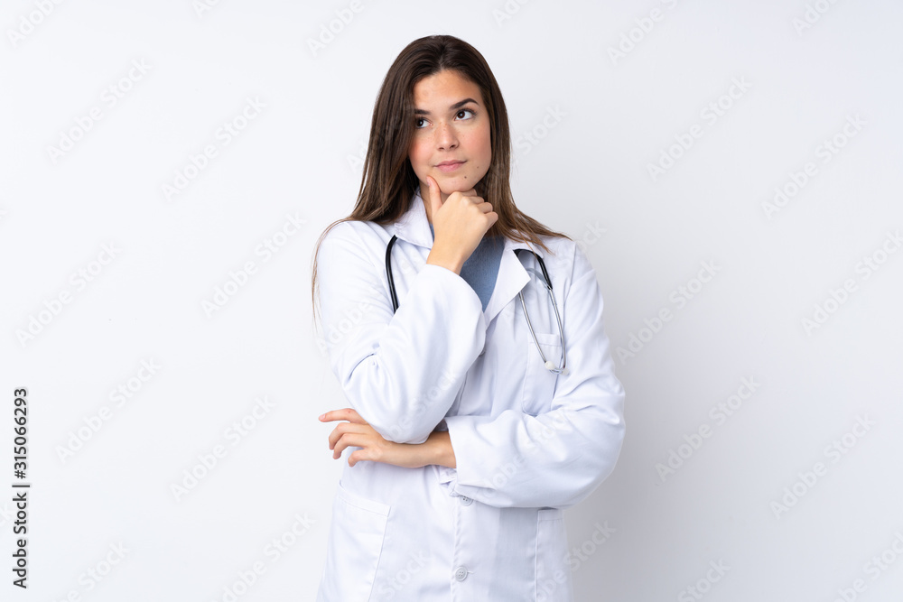 Teenager girl over isolated white background wearing a doctor gown and thinking Teenager girl over isolated white background wearing a doctor gown and thinking