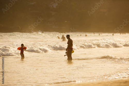Silhouette of mother enjoying a tropical beach with her children.