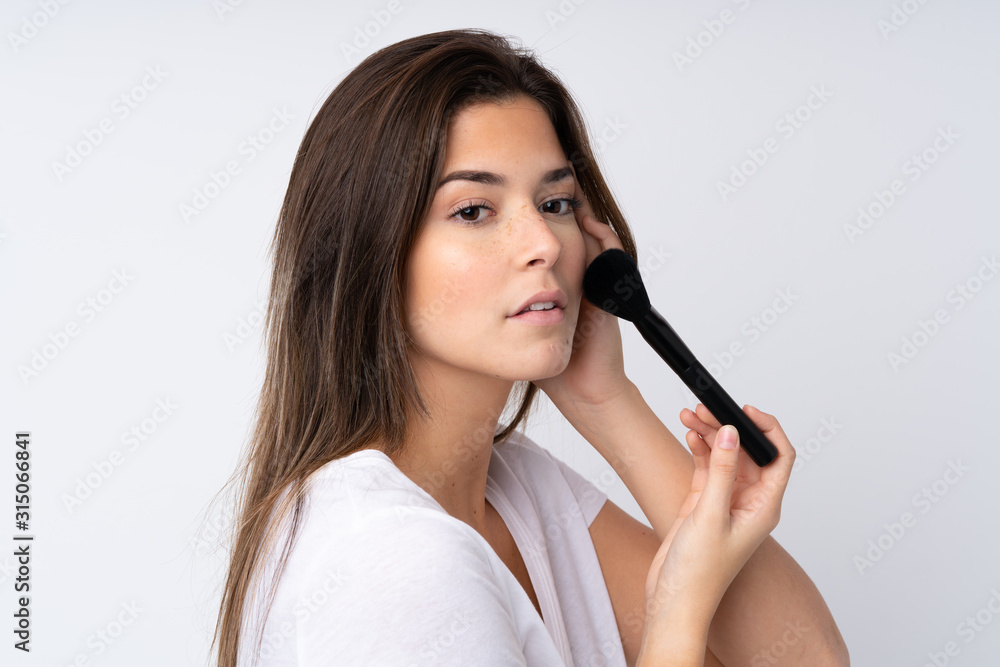 Teenager girl over isolated background holding makeup brush Teenager girl over isolated background holding makeup brush