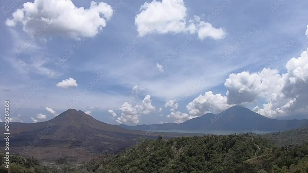Volcanic hills in north Bali with time lapsed clouds racing through the blue sky Volcanic hills in north Bali with time lapsed clouds racing through the blue sky
