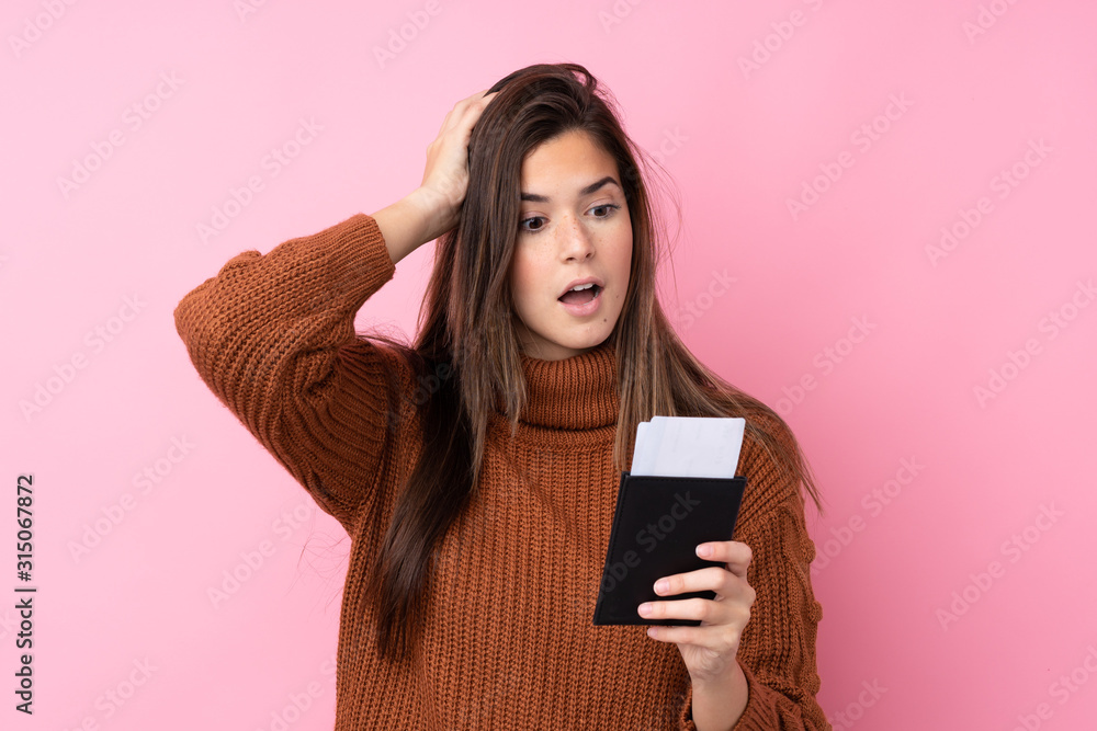 Teenager girl over isolated pink background in vacation with plane tickets and surprised Teenager girl over isolated pink background in vacation with plane tickets and surprised