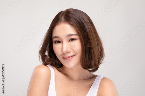 Beautiful Asian woman with short hair looking at camera smile with clean and fresh skin Happiness and cheerful with positive emotional isolated on gray background Beauty and Cosmetics Concept