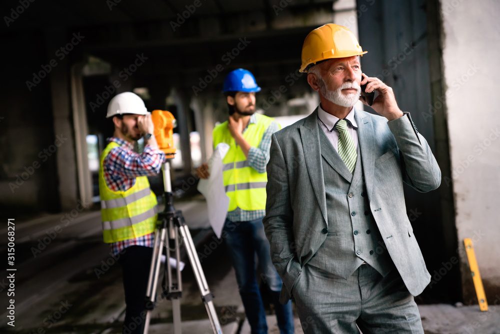 Confident team of architects and engineers working together on construction site Confident team of architects and engineers working together on construction site