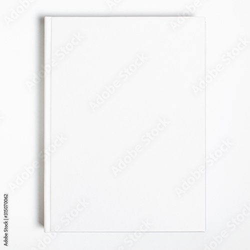 Mockup of closed blank square book at white textured paper background
