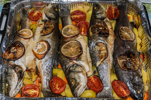 Roasted fish with vegetables and lemon in aluminum form