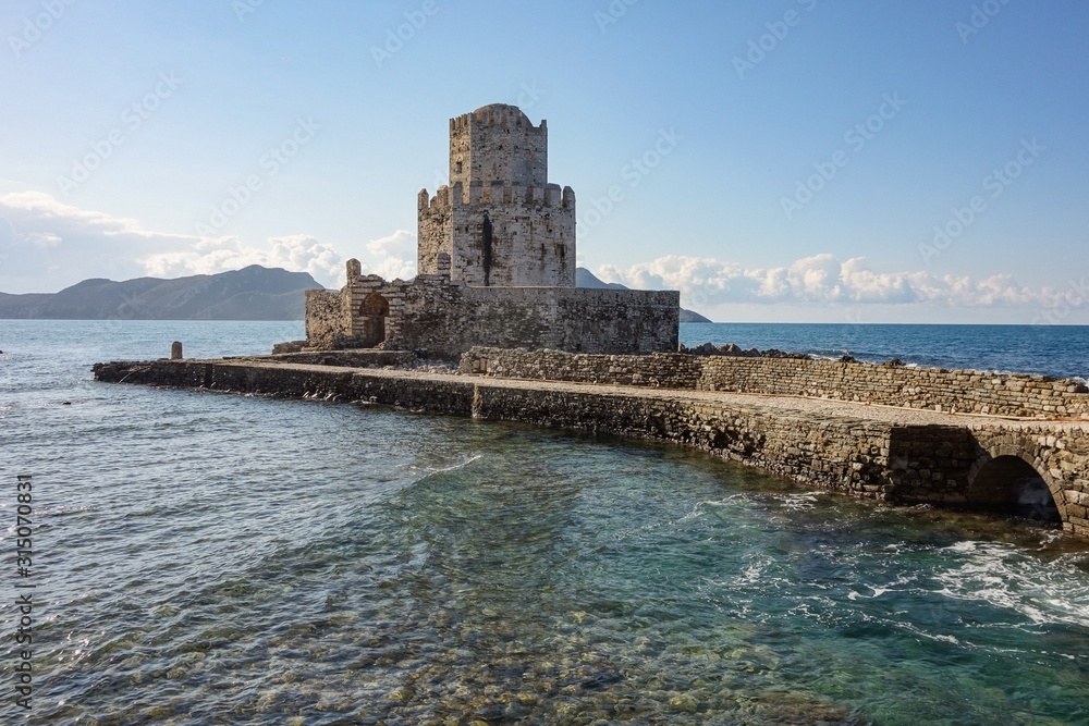 Methoni Castle with a bridge in sunny weather during early morning hours at sunrise with water waves in Greece