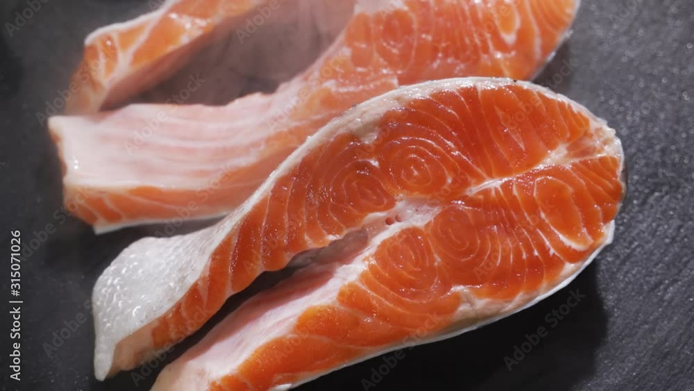 Raw, fresh salmon steak on a slate board and spices around. Raw salmon red fish. Cooking salmon, seafood. Raw, fresh salmon steak on a slate board and spices around. Raw salmon red fish. Cooking salmon, seafood.