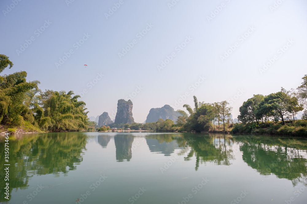 Lake with limestone karst hills foggy landscape reflecting in the river in Yangshuo, Guangxi province, China