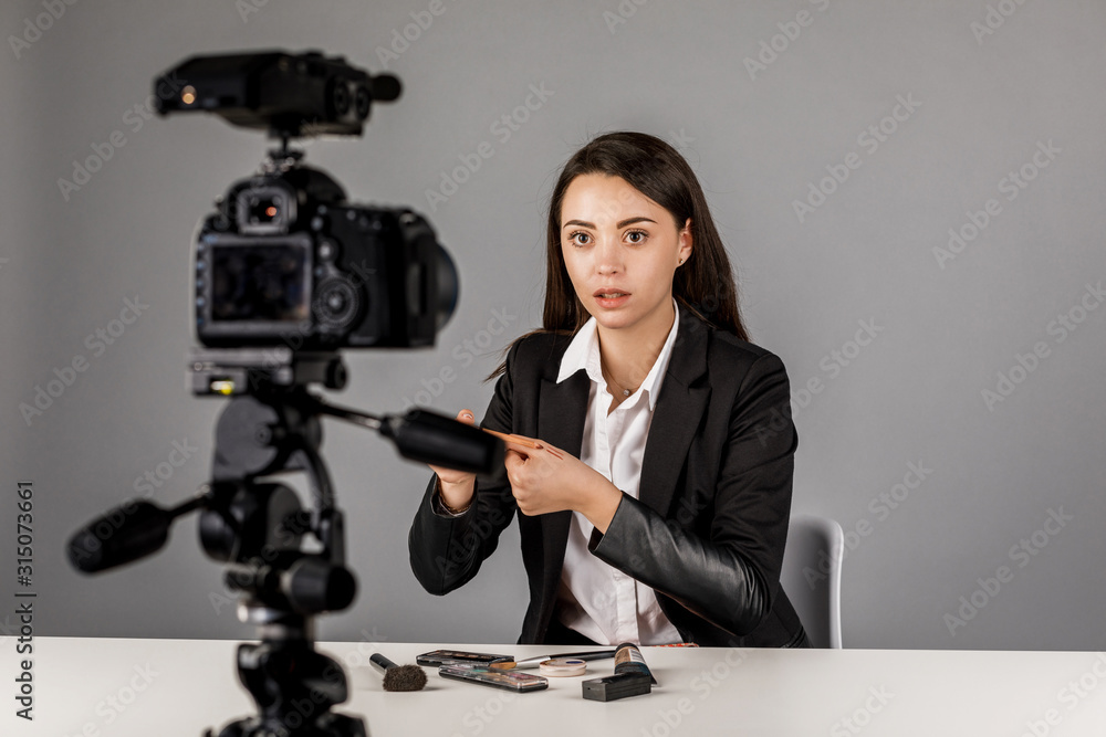 Young blogger in dark suite on grey background. Young blogger in dark suite on grey background.